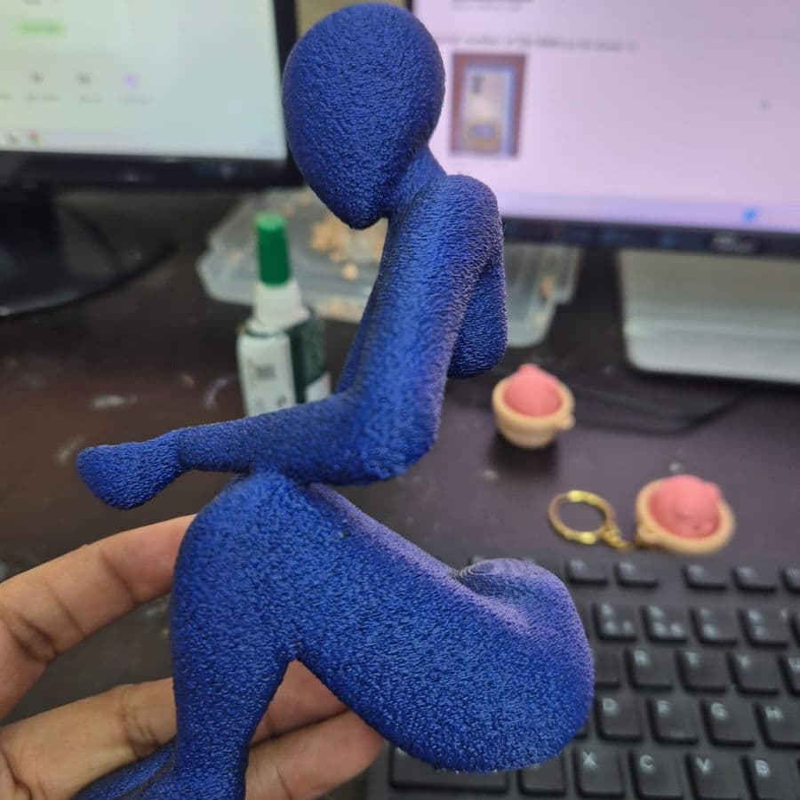 Blue textured figure sculpture being finished at the studio desk